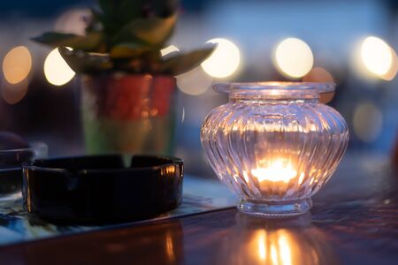 wooden table with ashtray and plant illuminated by romantic candle lightの写真素材