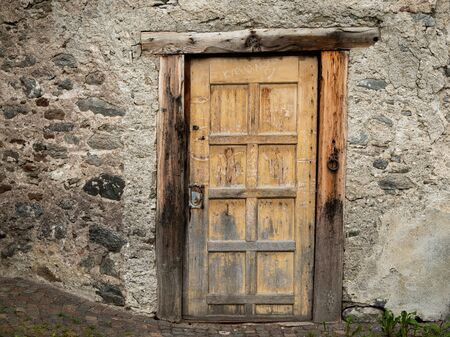 An old shabby wooden door of a stone house in Glurns (South Tyrol, ITaly)の写真素材