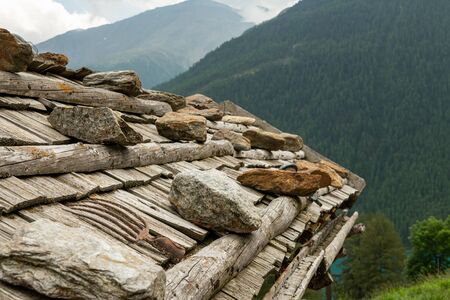 Closeup of an old wooden roof of a farmer house with rocks (South Tyrol, Italy)の写真素材