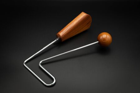 Closeup of a vibraslap silver, brown wood on black underground