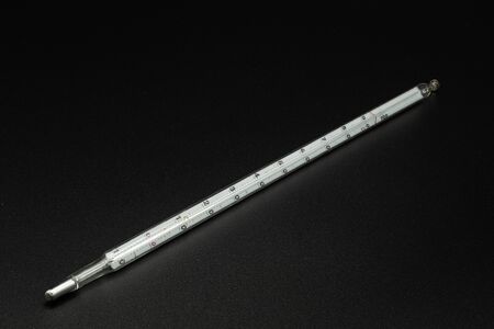 Closeup of an old mercury thermometer lying on a black background
