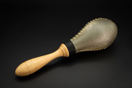 Closeup of a rawhide maracas lying on a black underground