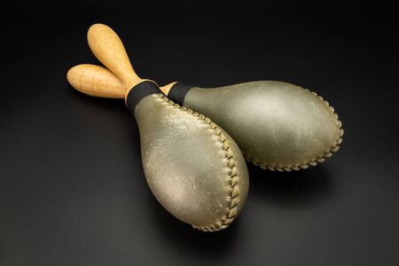 Closeup of a pair of rawhide maracas lying on a black underground