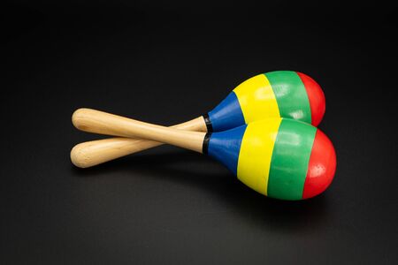 Closeup of a pair of colorful maracas lying on a black underground