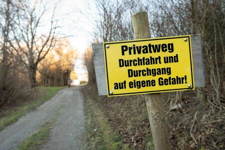 Yellow signpost for a private road in german meaning "Private road passage at your own risk"の写真素材