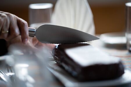 Closeup of someone cutting a chocolate cake with a knife