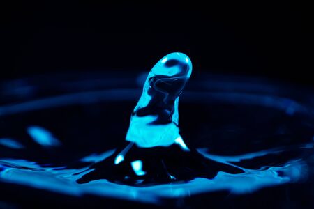 Closeup of a single water droplet hitting the surface, dark blueの写真素材