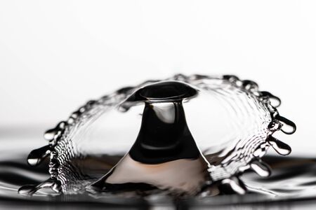 Closeup of collision of two water droplets hitting the surface, white backgroundの写真素材