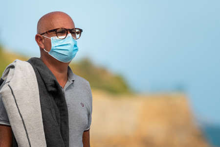 Perros-Guirec, France - August 23, 2020: Man wearing a mask on the street outdoors, protection against corona virus infection, sunny day in summer on the beachのeditorial素材