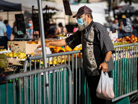 Chalon en Champagne, France - August 07, 2020: Man with face mask buying on a market on a hot sunny day in summerのeditorial素材