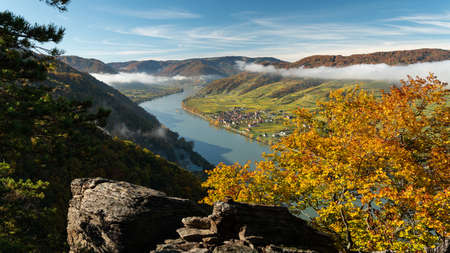 Wachau (Austria) valley on a sunny day in autumn, colored leaves, low cloudsの写真素材