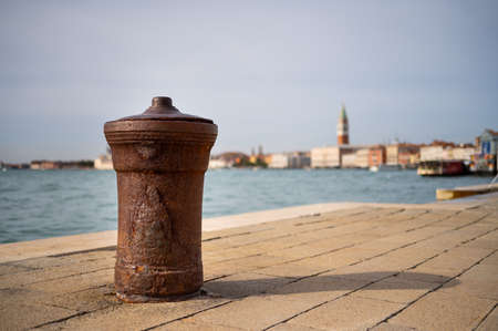 Rusty bollard, Campanile and Doge palace in Venice (Italy), sunny day in autumn
