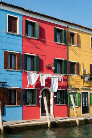 Burano, Italy - October 29, 2021: Colorful houses of Burano on a sunny day in autumn, clear sky, laundry hung out for dryingwith boatのeditorial素材