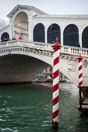 Venice, Italy - October 25, 2021: Red white striped poles in front of Rialto bridge, cloudy day in autumnのeditorial素材