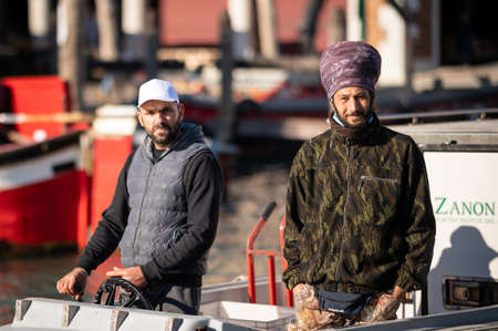 Venice, Italy - October 28, 2021: 2 Men steering a transportation boat on the Canale Grande in Venice, sunny day in winterのeditorial素材