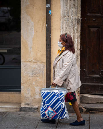 Nancy, France - September 2, 2020: Woman with face mask walking and carrying bagsのeditorial素材