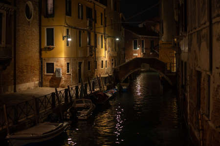 Venice, Italy - October 31, 2021: Canal with boats in the night in autumn, reflection of streetlights in the waterのeditorial素材
