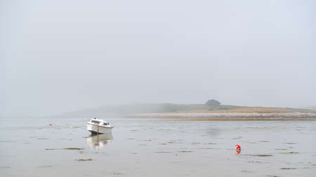 Lanilis, France - August 11, 2020: Old small boat lying on the beach, low tide, foggy day in summerのeditorial素材