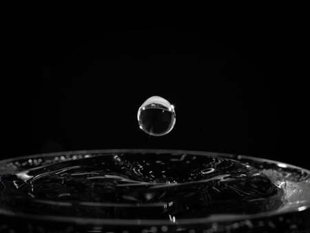 Closeup of a single water droplet hitting the surface, black and whiteの写真素材