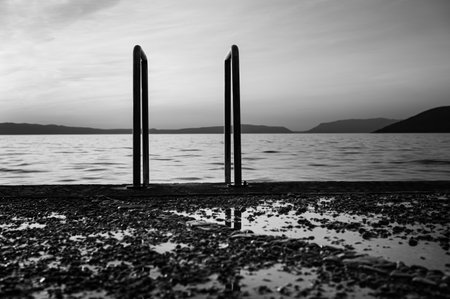 Ladder into the sea at the beach in Cres (Croatia), sunset in springtime, reflections in puddleの写真素材