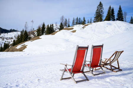 Two red chairs standing in the snow on a mountain, sunny day in winter, Austrian Alpsの写真素材