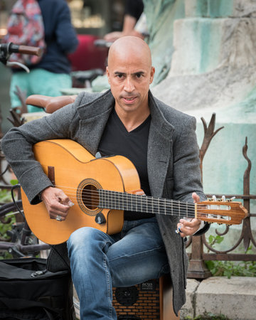 La Rochelle, France - August 24, 2018: Bald street musician playing the guitar, sunny day in summer