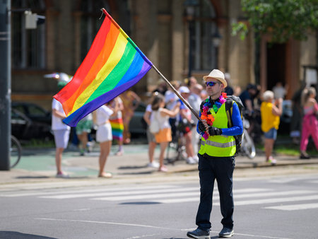 Vienna, Austria - June 08, 2024: People at Vienna Pride in summer on Wiener Ringstrasse, man walking with large flagのeditorial素材