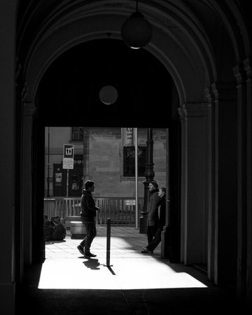 Vienna, Austria - February 2, 2021: Walking person silhouetted in archway with dramatic backlight and shadow on groundのeditorial素材