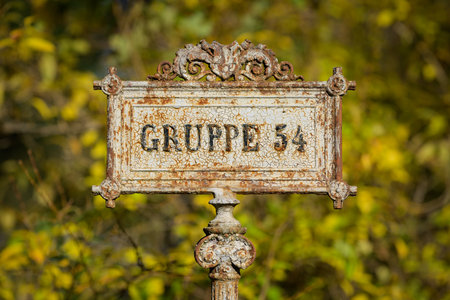 Old iron sign marking group of graves at Vienna Zentralfriedhof on autumn day with colorful foliageの写真素材