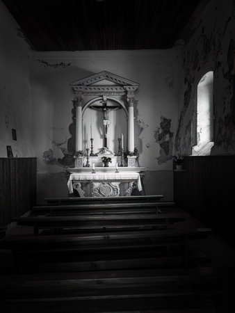 Cres, Croatia - April 4, 2023: An altar of a small chapel is illuminated by a side window in black and white.のeditorial素材