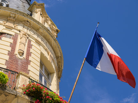 Trouville-sur-Mer, France - July 26, 2022: A French flag waves before a blue sky and house facade on a sunny summer day.のeditorial素材