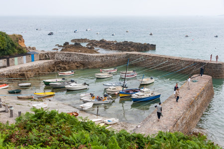 Saint-Germain-des-Vaux, France - August 17, 2016: A small harbor with boats lies under a cloudy summer sky creating a maritime view.のeditorial素材