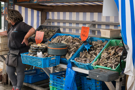Cancale, France - August 13, 2018: A street stall sells oysters in Cancale France on a cloudy summer day with vendor present.のeditorial素材