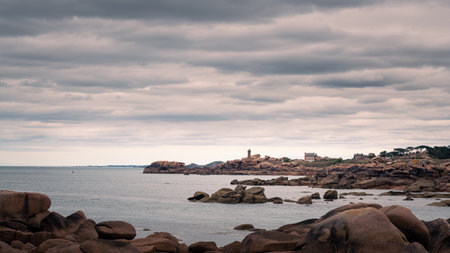 Rocky pink granite coast in Tregastel France under cloudy summer sky showing dramatic shoreline and natural formationsの写真素材