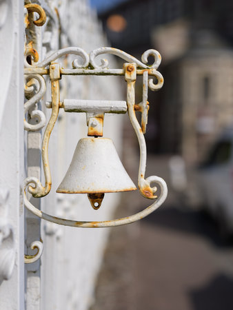 A small white metal bell is attached to the outside wall of a house in Yport, France during summer season.の写真素材