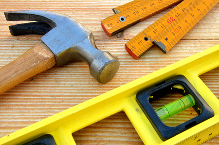 Claw hammer, carpenter meter, water-level on wooden desk background