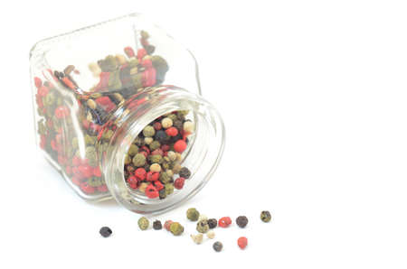 Colored pepper spilled from glass bottle isolated on white backgroundの写真素材