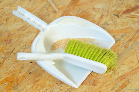 Plastic brush and dustpan with sawdust placed on OSB boardの写真素材