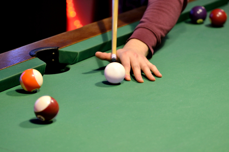 Close-up of pool player hits the cue ball