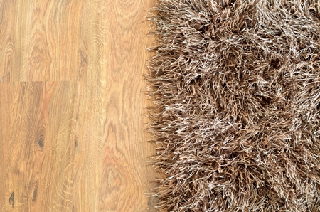 Two part split image of brown shaggy carpet and wooden floor. Photo from top.の写真素材
