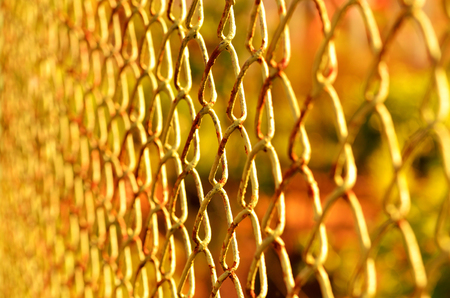 Old rusty chain-link fence at orange sunsetの写真素材