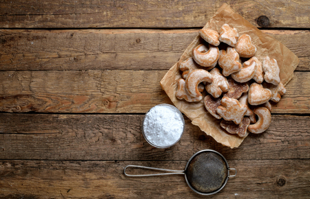 View from above of differently shaped gingerbread on baking paper, sieve and icing sugar on rustic wooden boardsの写真素材