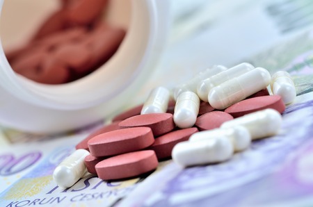 Tablets on Czech banknotes and bottle with pills in background - medical or pharmaceutical industry business finance conceptの写真素材