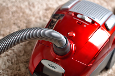 Vacuum cleaner on shaggy carpet - close-up of modern red hooverの写真素材
