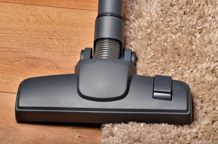 Close-up of head of vacuum cleaner on borderline of shaggy carpet and floating floorの写真素材