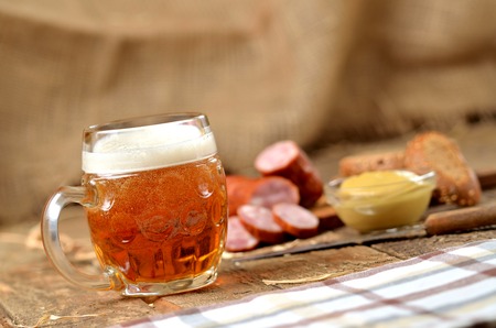 Glass of beer, sausage, mustard and bread in the backgroundの写真素材