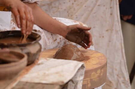 Female potters hands shaping up the lump of clay pot on wheal.の写真素材