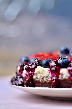 Detail of cheesecake tart with fresh strawberries, blueberries and cherry jam. Vertical photo.の写真素材