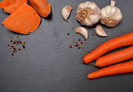 Fresh sliced pumpkin, carrot, garlic and colored pepper on slate plate. Top view. Copyspace.の写真素材