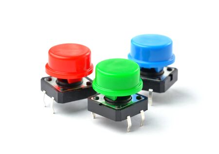Small electronic tactile toggle push buttons switch with multicolored hats isolated on white...